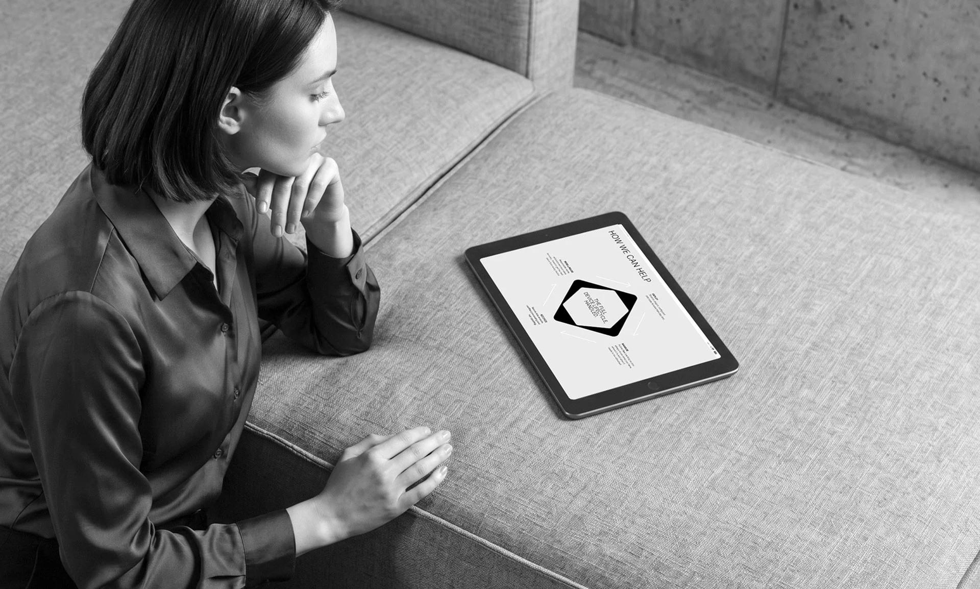 Woman sitting on couch looking thoughtfully at a tablet