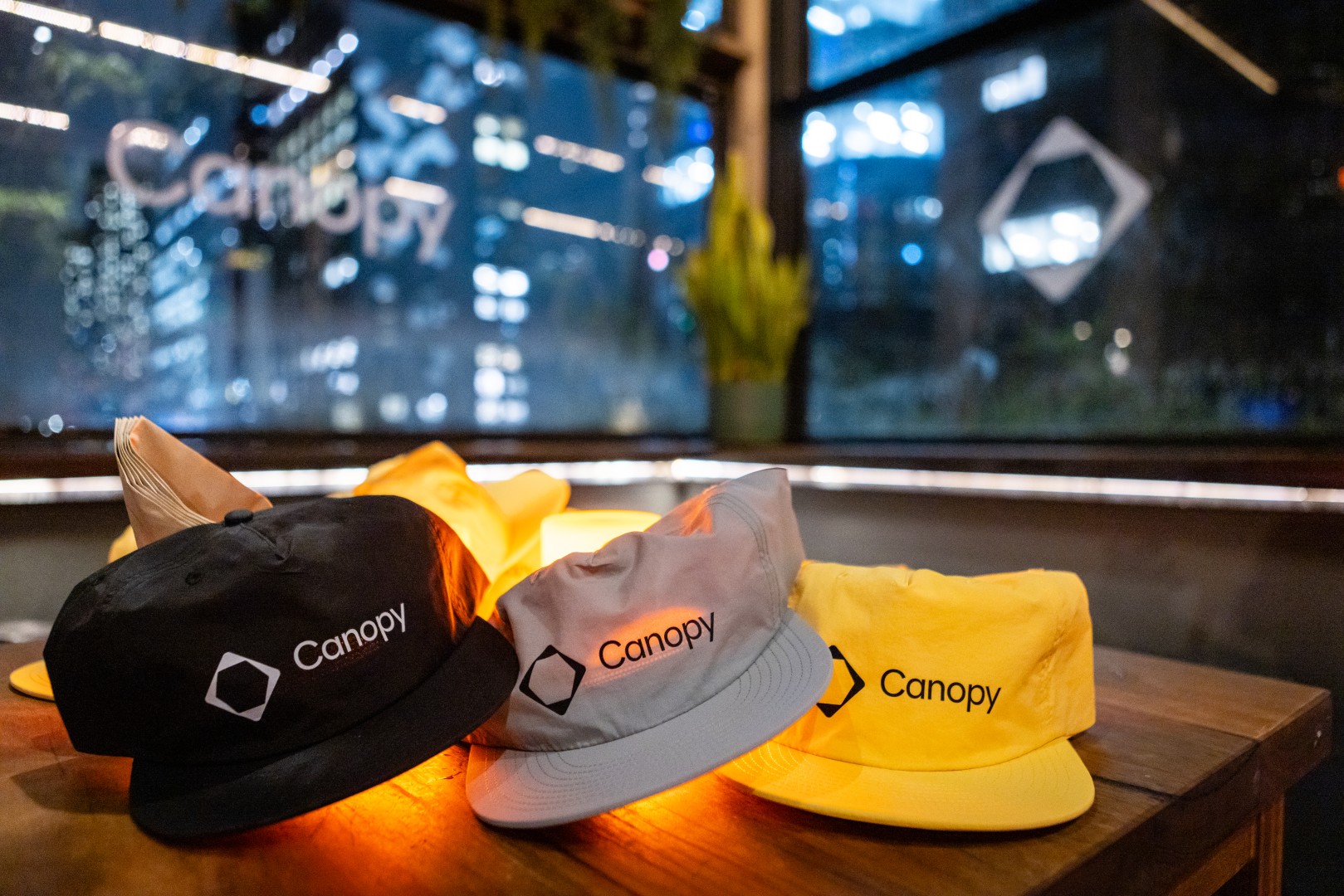 Canopy caps on a table by the Canopy logo window at Bomba Rooftop Bar