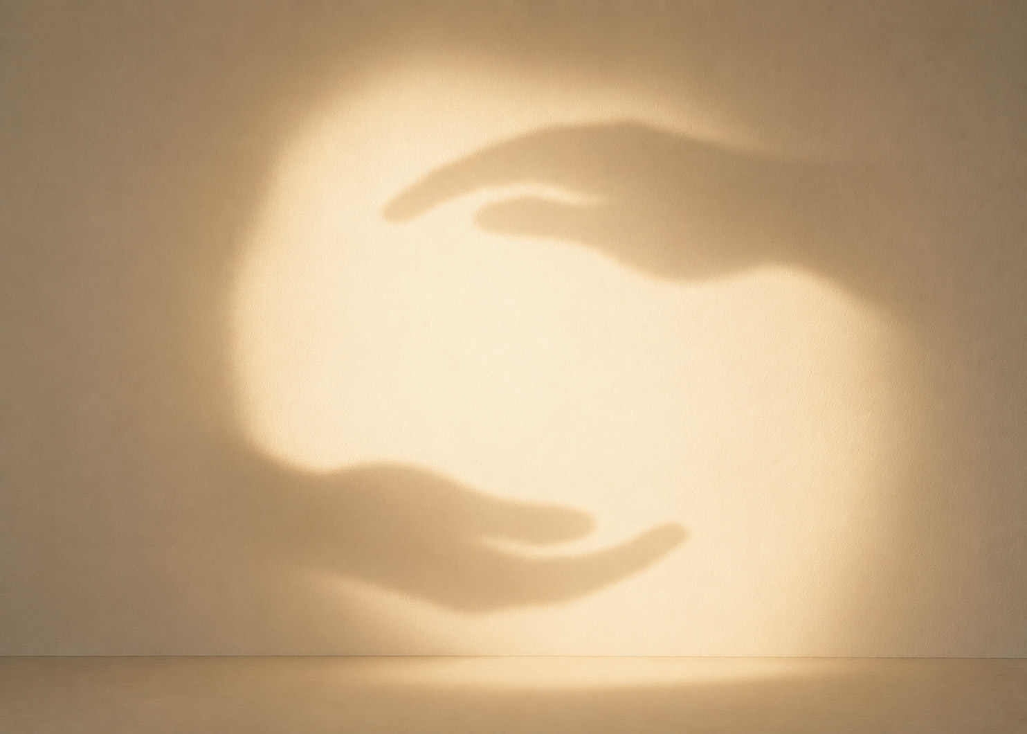 Schattenspiel zweier Hände, die gemeinsam einen Lichtkreis formen