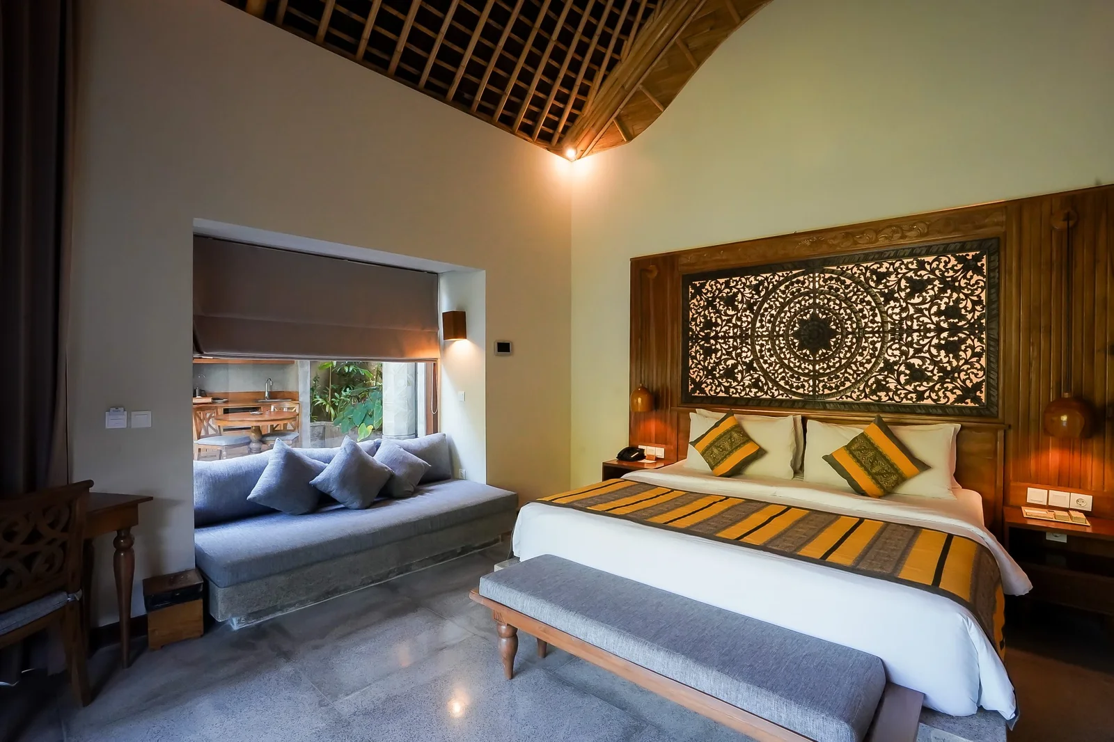 A Kenran suite with a carved timber headboard beneath a high alang-alang ceiling