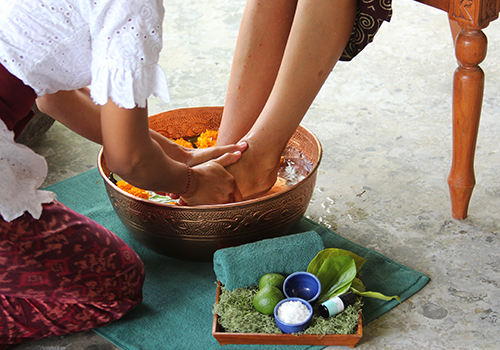 A welcome foot bath in a copper bowl scattered with marigold petals