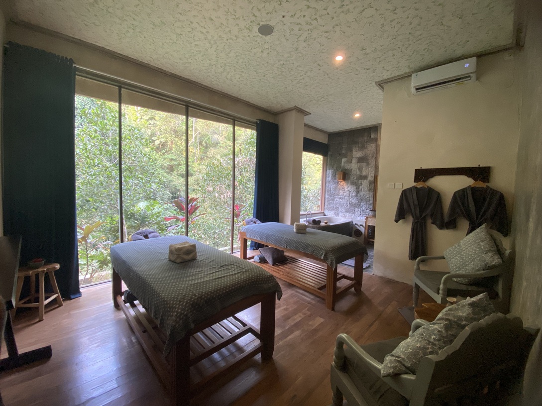 Jamu Spa treatment room with two massage beds overlooking tropical greenery