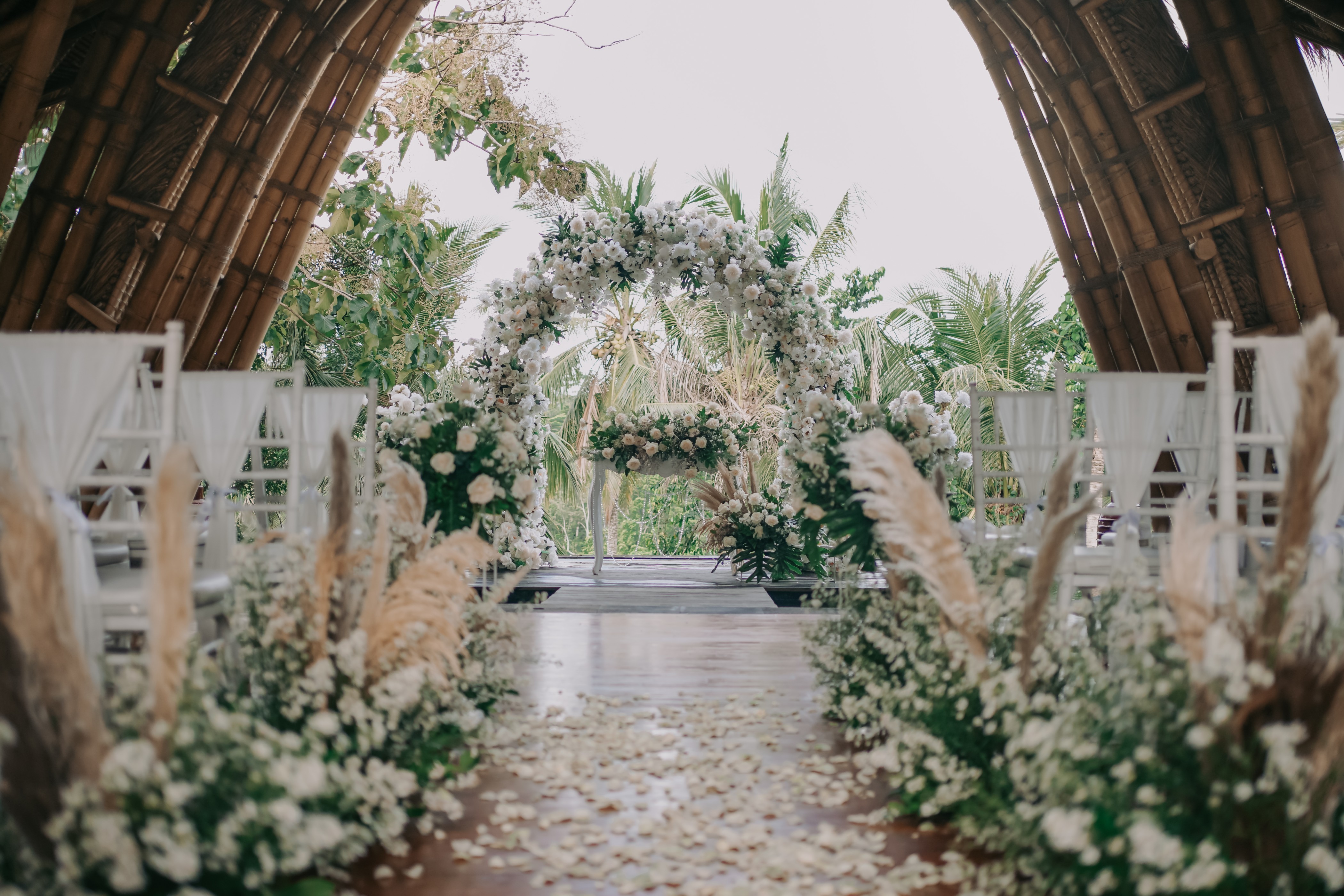 A long banquet table dressed for a wedding reception beneath the bamboo pavilion at Kenran Resort Ubud
