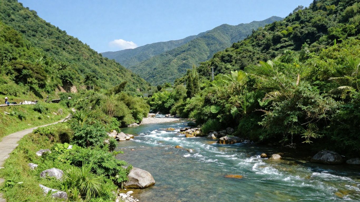 Green watershed with river and mountains under blue sky.