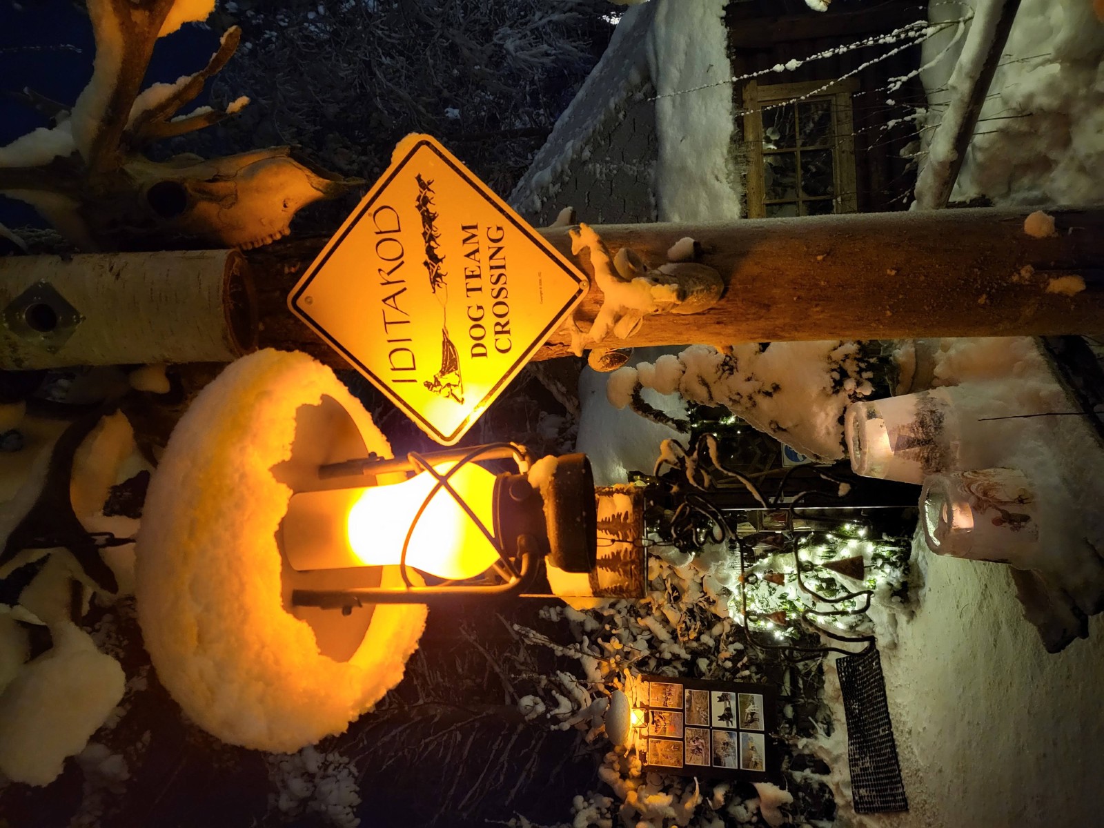 Snow-covered lantern and Tundra Huskies sign at night