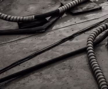 Close-up of wrapped cables and wires lying on a concrete floor in black and white.