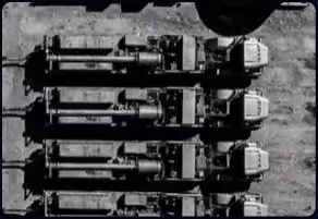 Aerial view of four large industrial trucks parked side by side on a concrete surface.