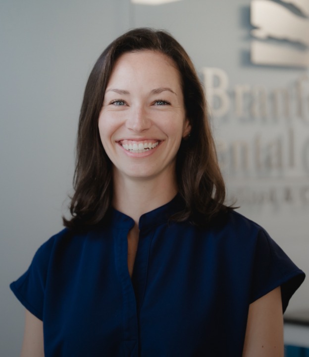 Smiling woman with brown hair wearing a navy blouse in a professional setting.