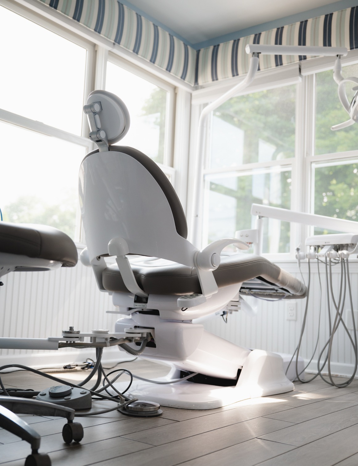 Modern dental chair near large windows with dental equipment in bright office.