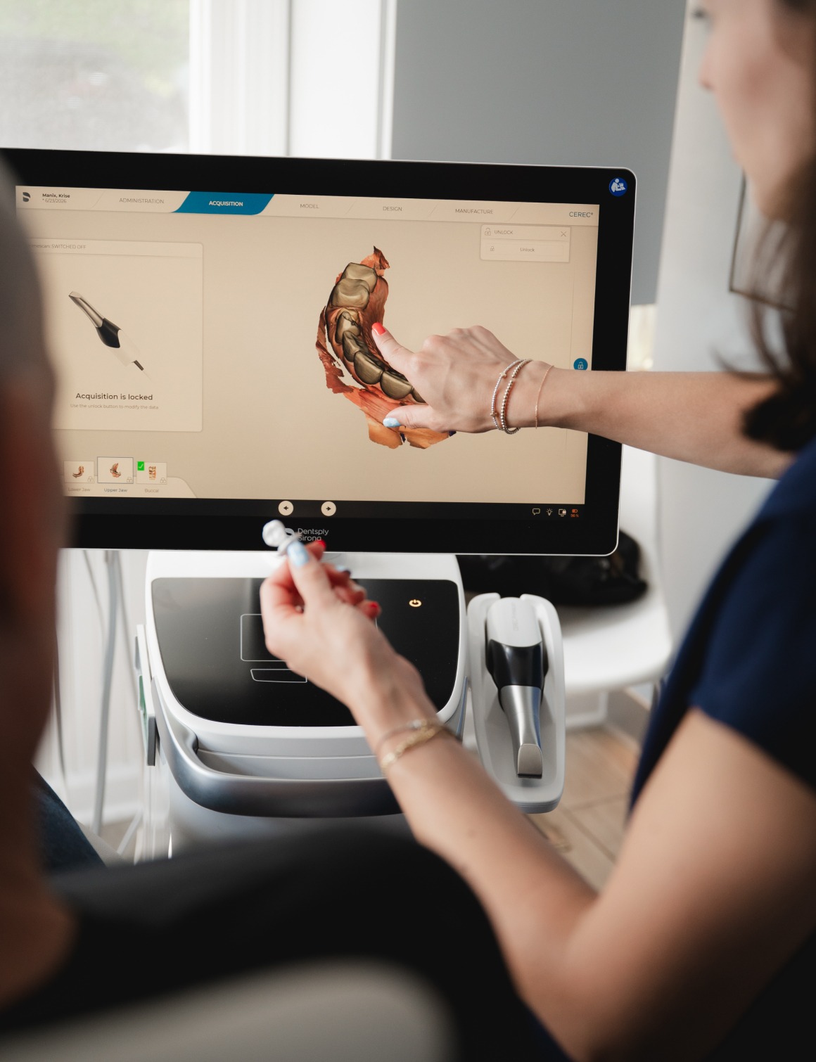 Dental professional explaining a 3D dental scan on a monitor to a patient.