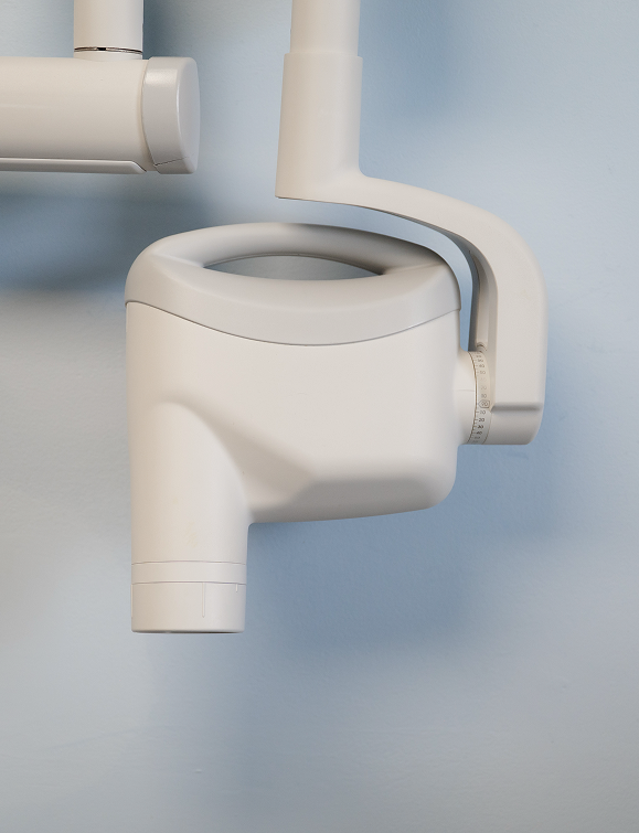 Close-up of a white dental X-ray machine arm against a light blue wall.