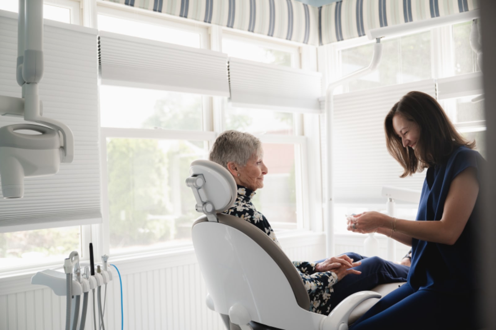 Dentist explaining treatment to seated patient in clinical setting
