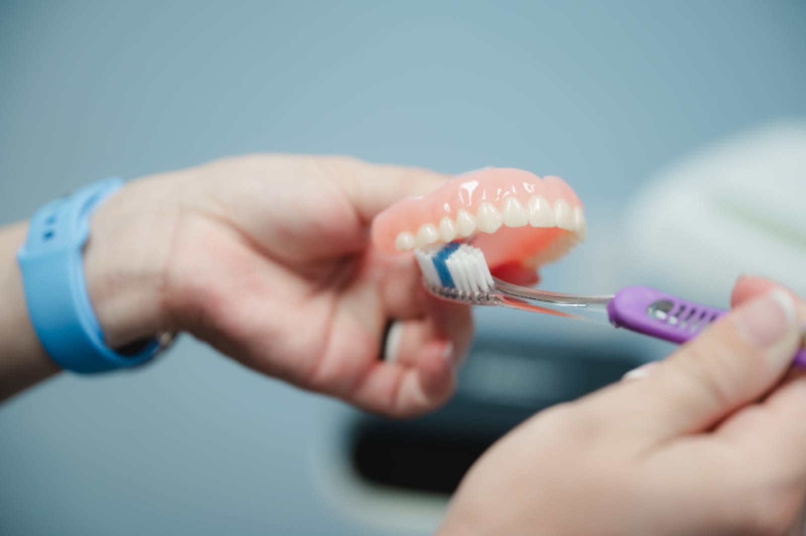 Close-up of hands demonstrating proper tooth brushing technique with a colorful toothbrush.