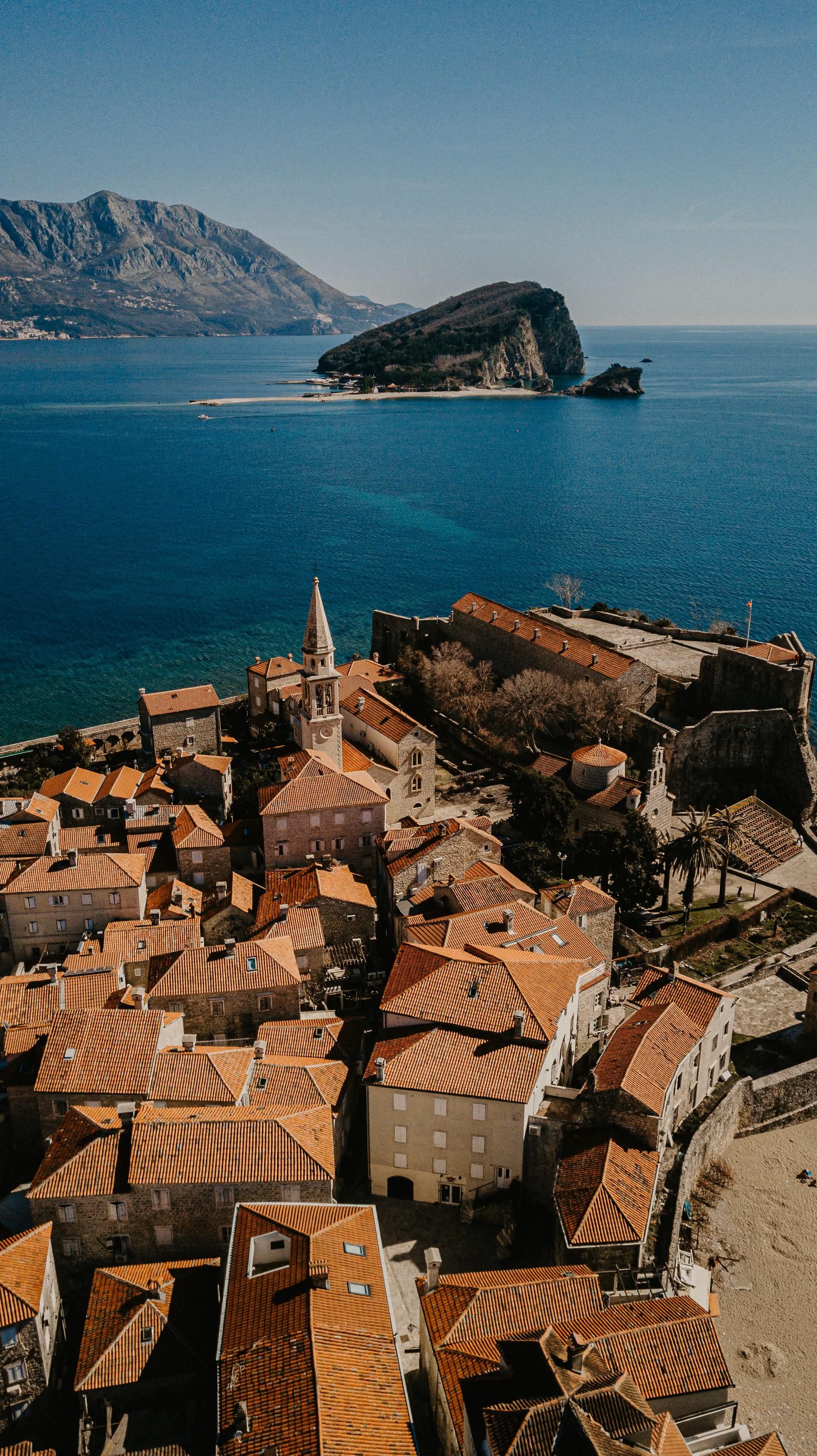 Aerial view of a red-roofed Adriatic old town with a small island offshore