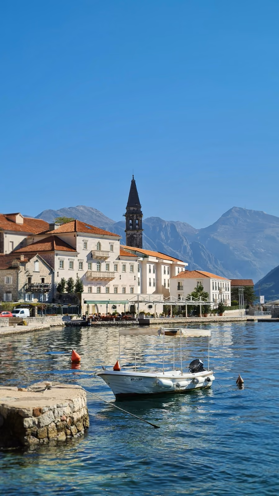 Waterfront old town with a stone bell tower and a boat moored on the Adriatic