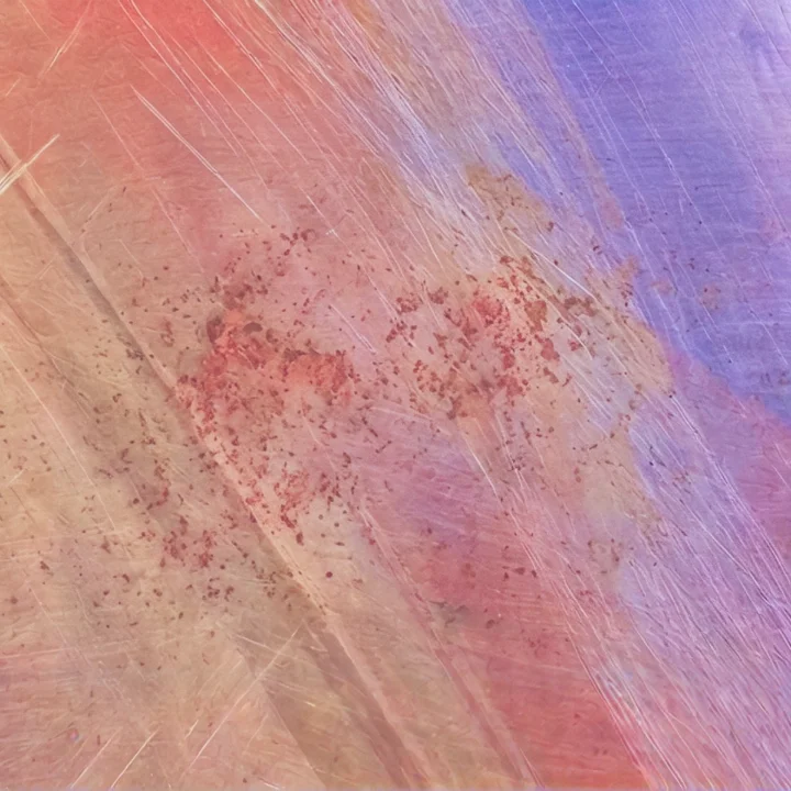 Abstract brushed metal surface in warm pinks, golds and violets.