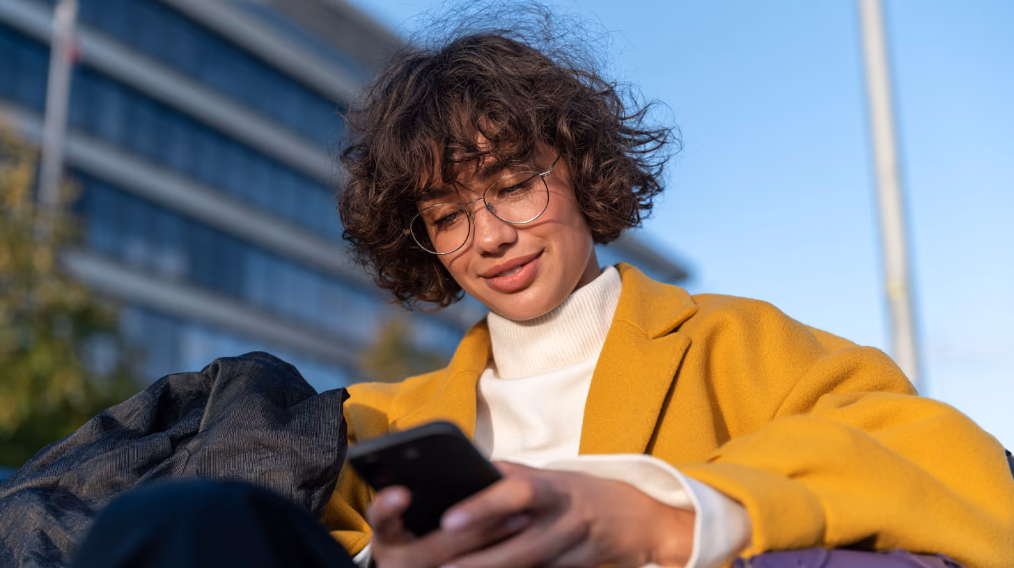 Person bedient ihr Smartphone im Freien