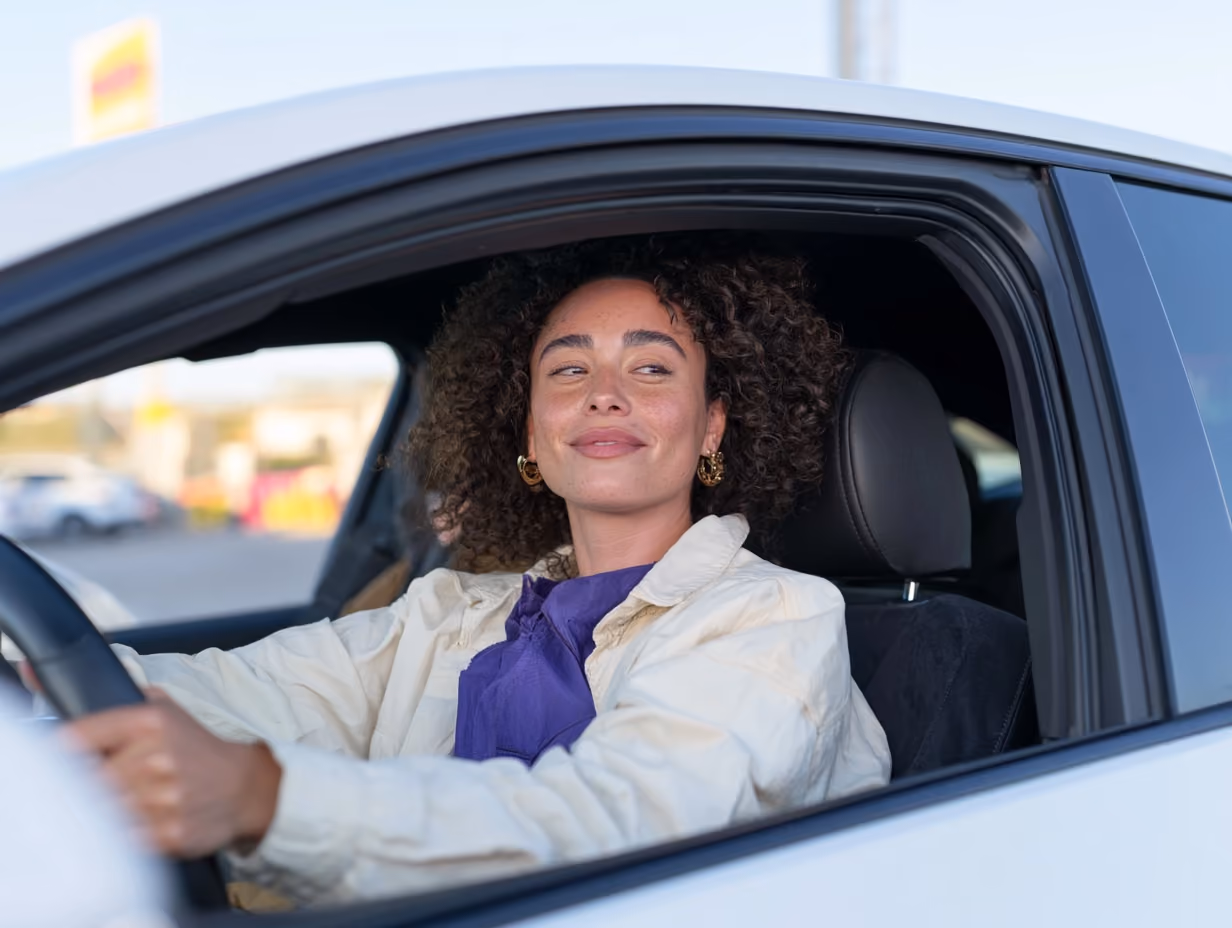 Frau sitzt lächelnd in ihrem Auto