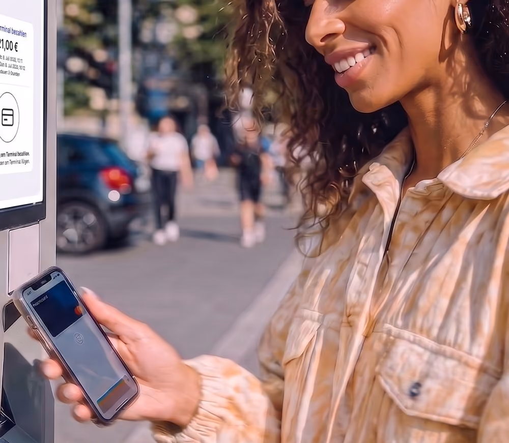 Hand mit Handy vor dem Parkautomaten, davor die Auswahl zwischen Münzen und Karte