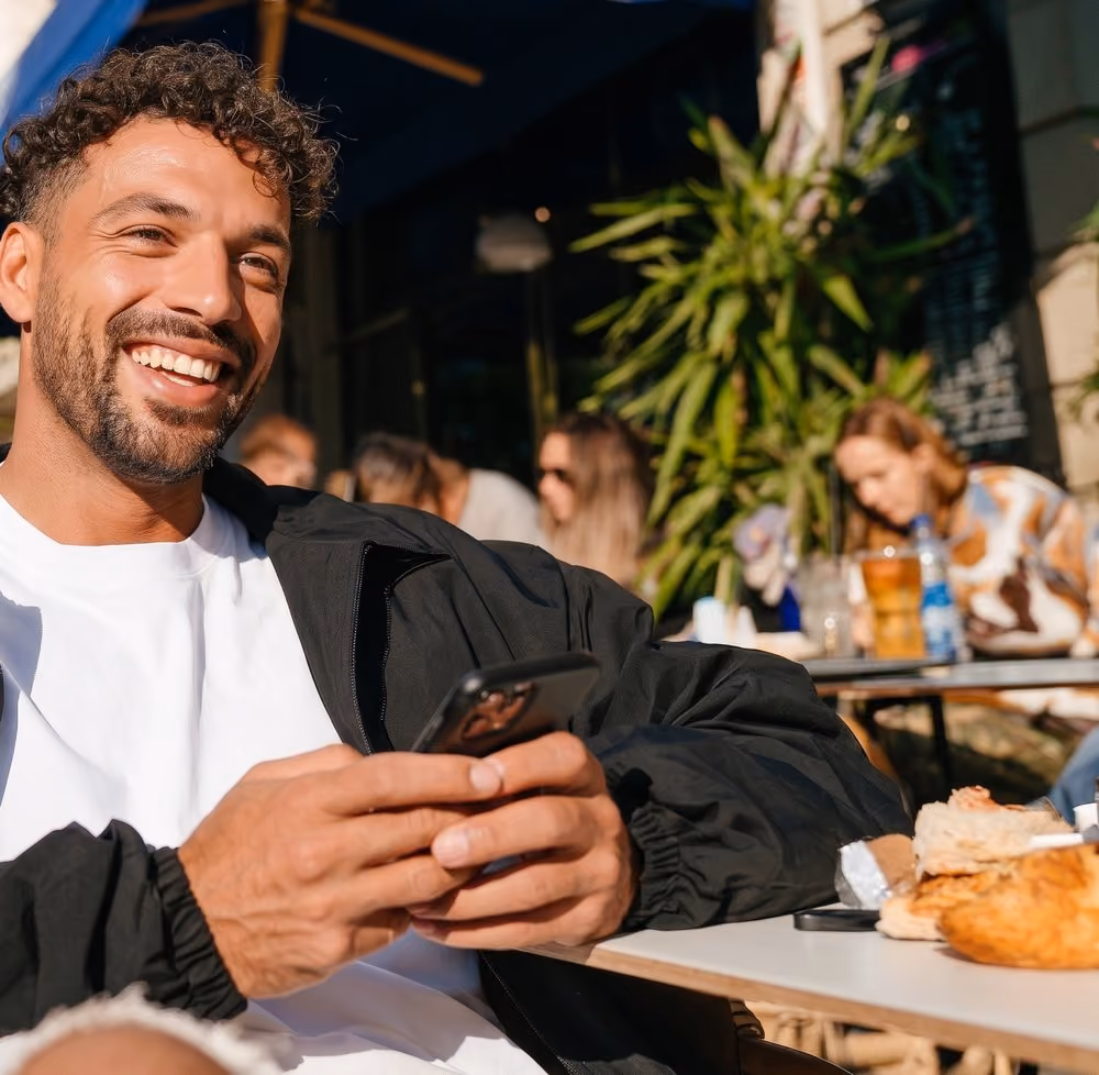 Mann mit Handy, davor die Mobile-Payment-Seite mit Kennzeicheneingabe