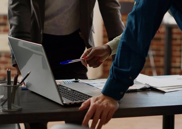 Hands pointing at a laptop during a meeting