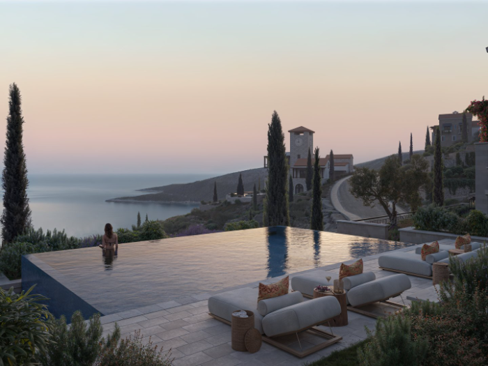 Infinity pool terrace at dusk with sun loungers, cypress trees and Adriatic views