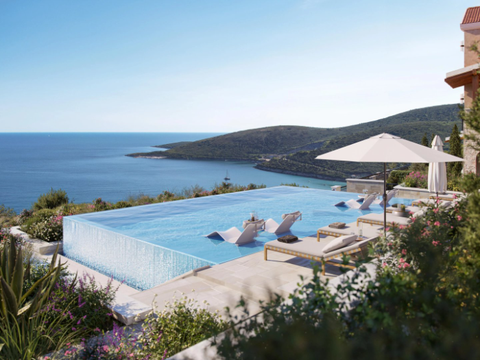 Outdoor swimming pool with sun loungers and parasols above the sea
