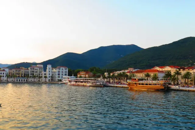 Waterfront promenade at sunset with moored boats and mountains in Montenegro