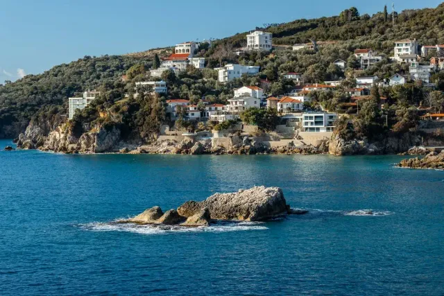 Rocky Albanian coastline with houses above turquoise sea