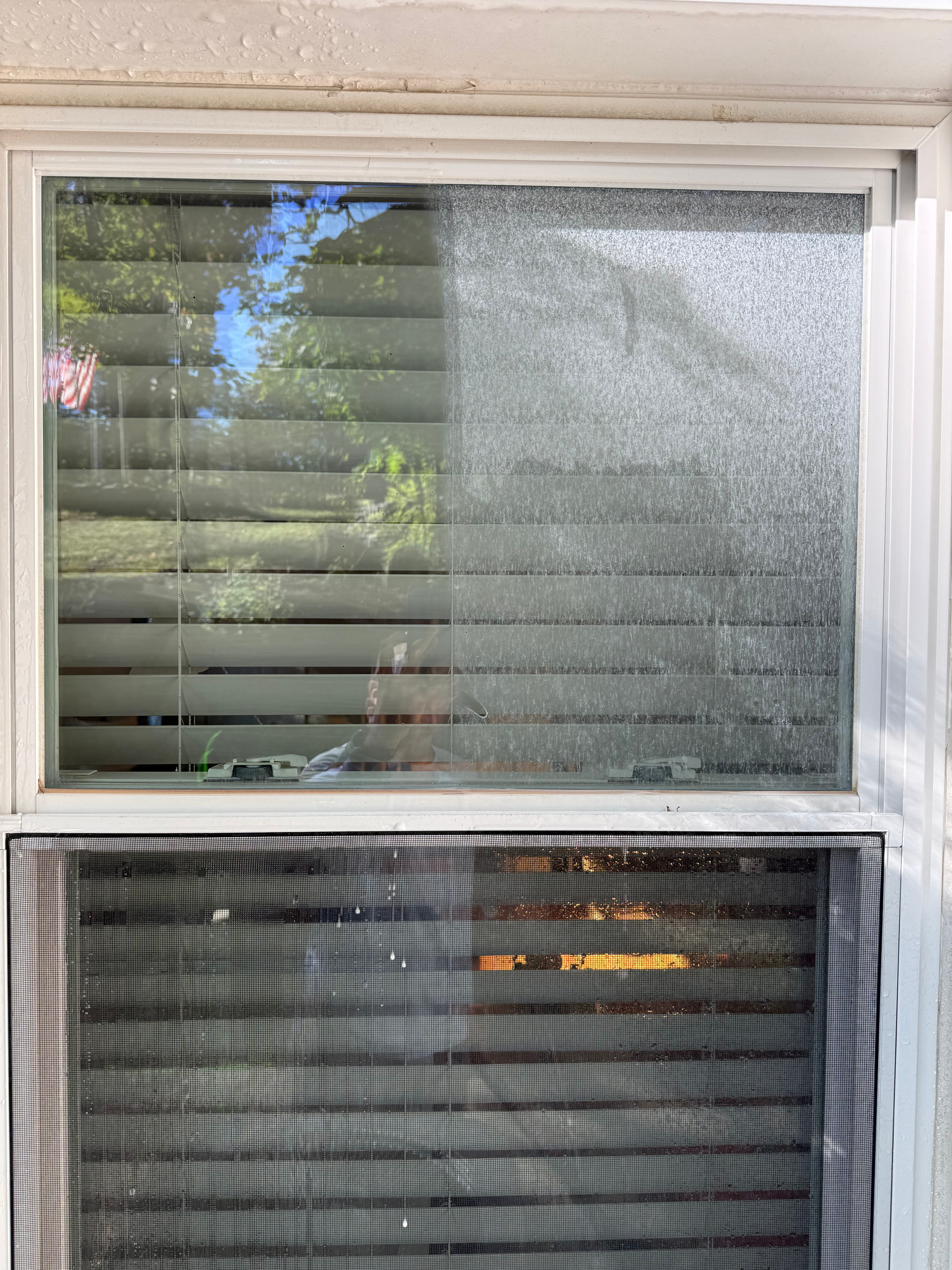 Exterior glass being washed by hand, soapy water running down the pane