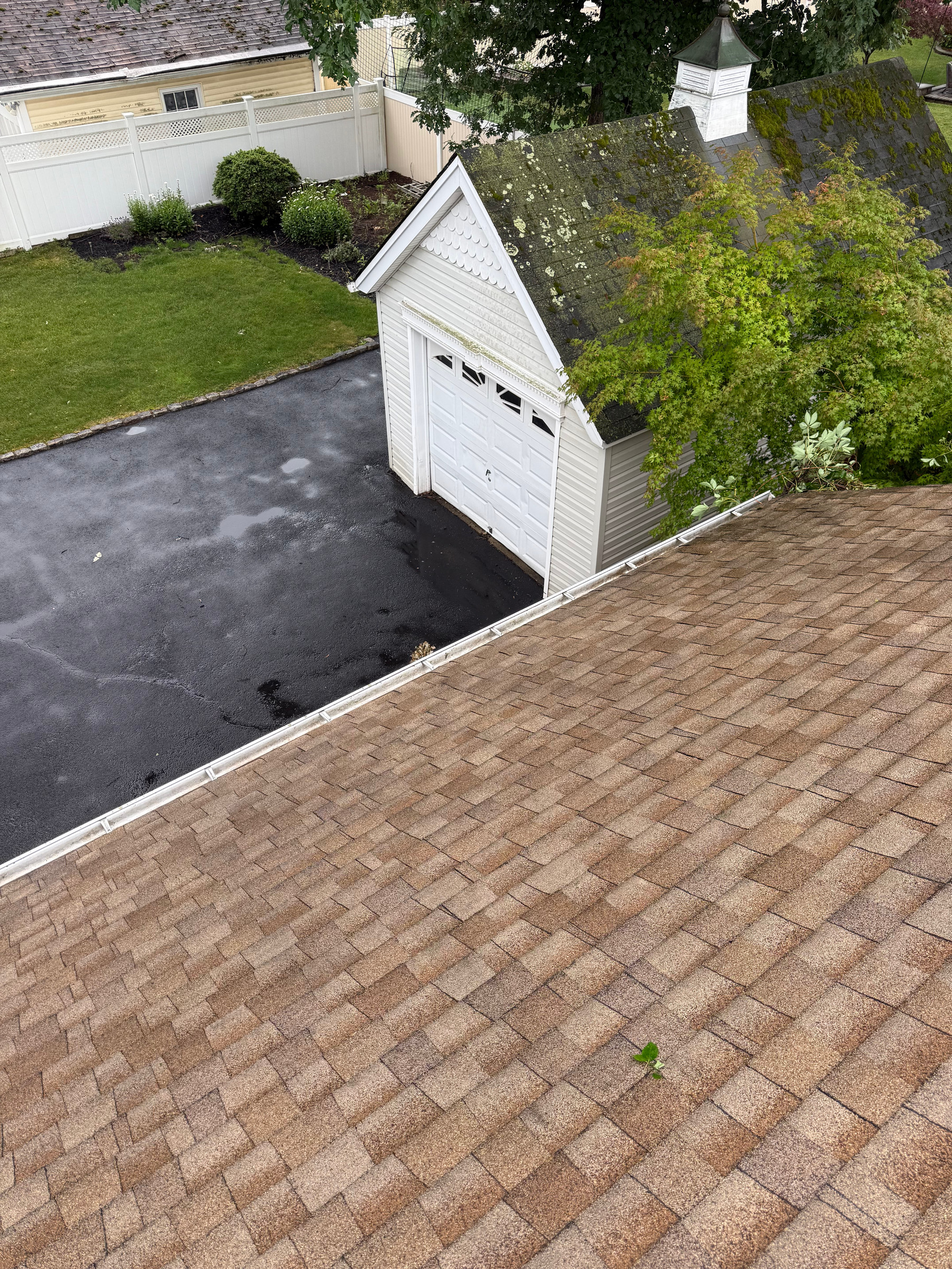 Clear gutter run along a shingle roof edge, seen from an upstairs window