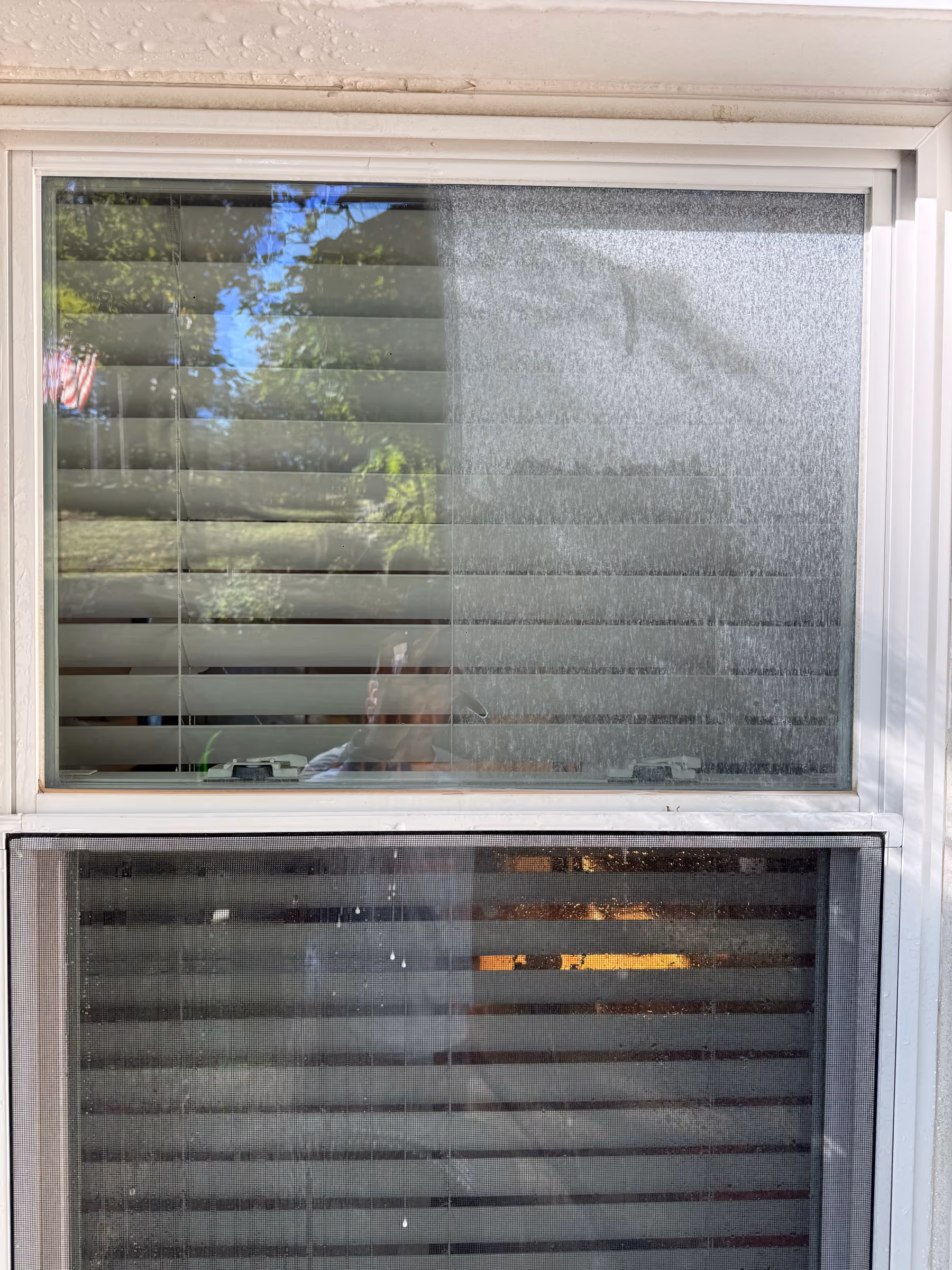 Exterior glass being washed by hand, soapy water running down the pane