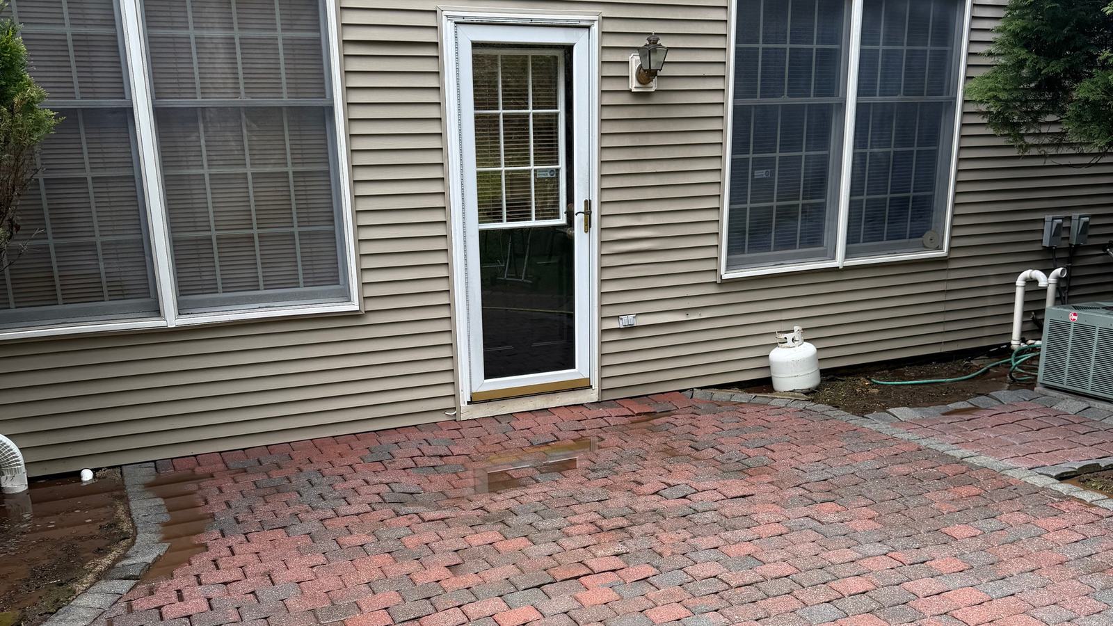 Red brick paver patio beside a home after cleaning, original color restored