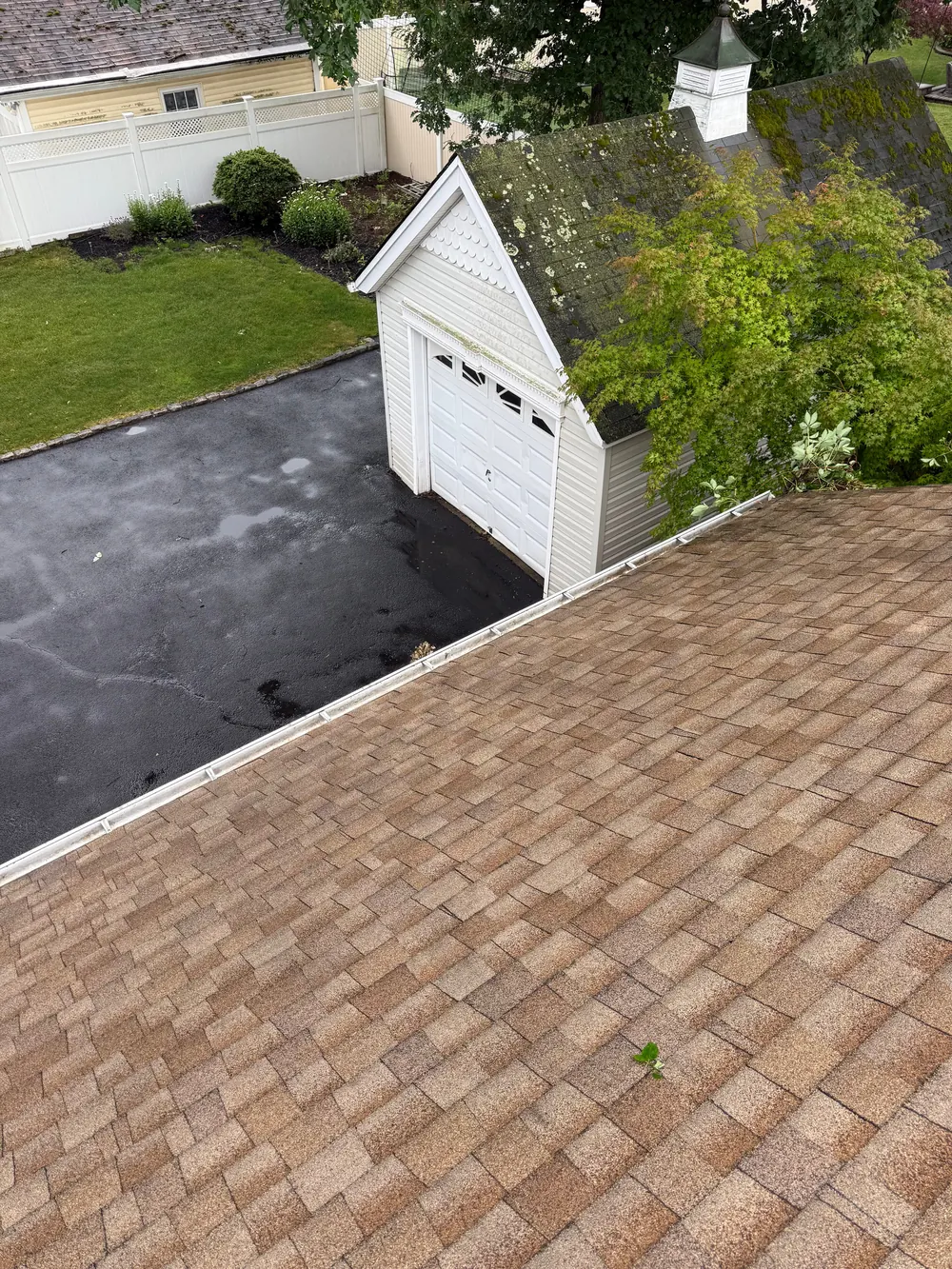 Clear gutter run along a shingle roof edge, seen from an upstairs window