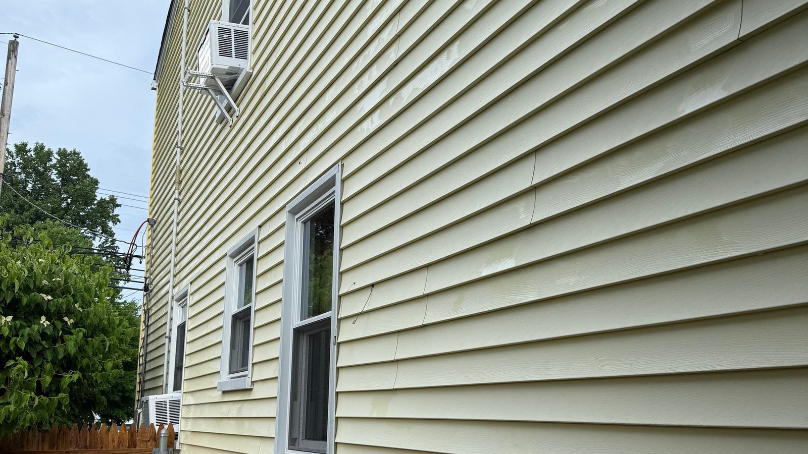 Cream vinyl siding on a North Jersey home after a soft wash, algae removed and color even