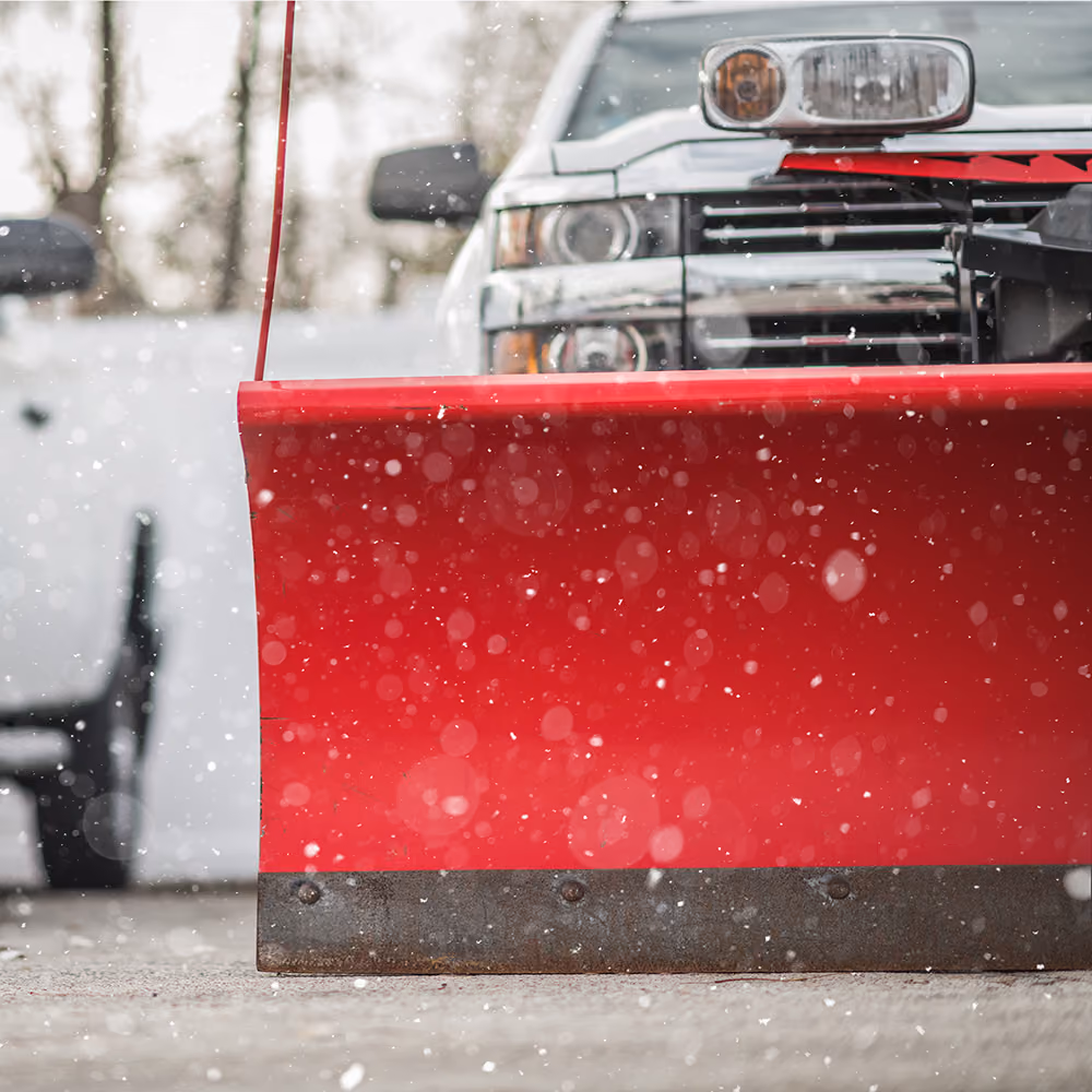 Snow plowing truck clearing commercial parking lot Triscapes