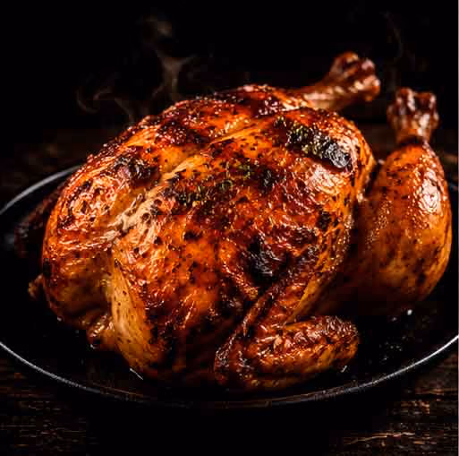 Whole roasted chicken with crispy golden-brown skin on a dark plate.