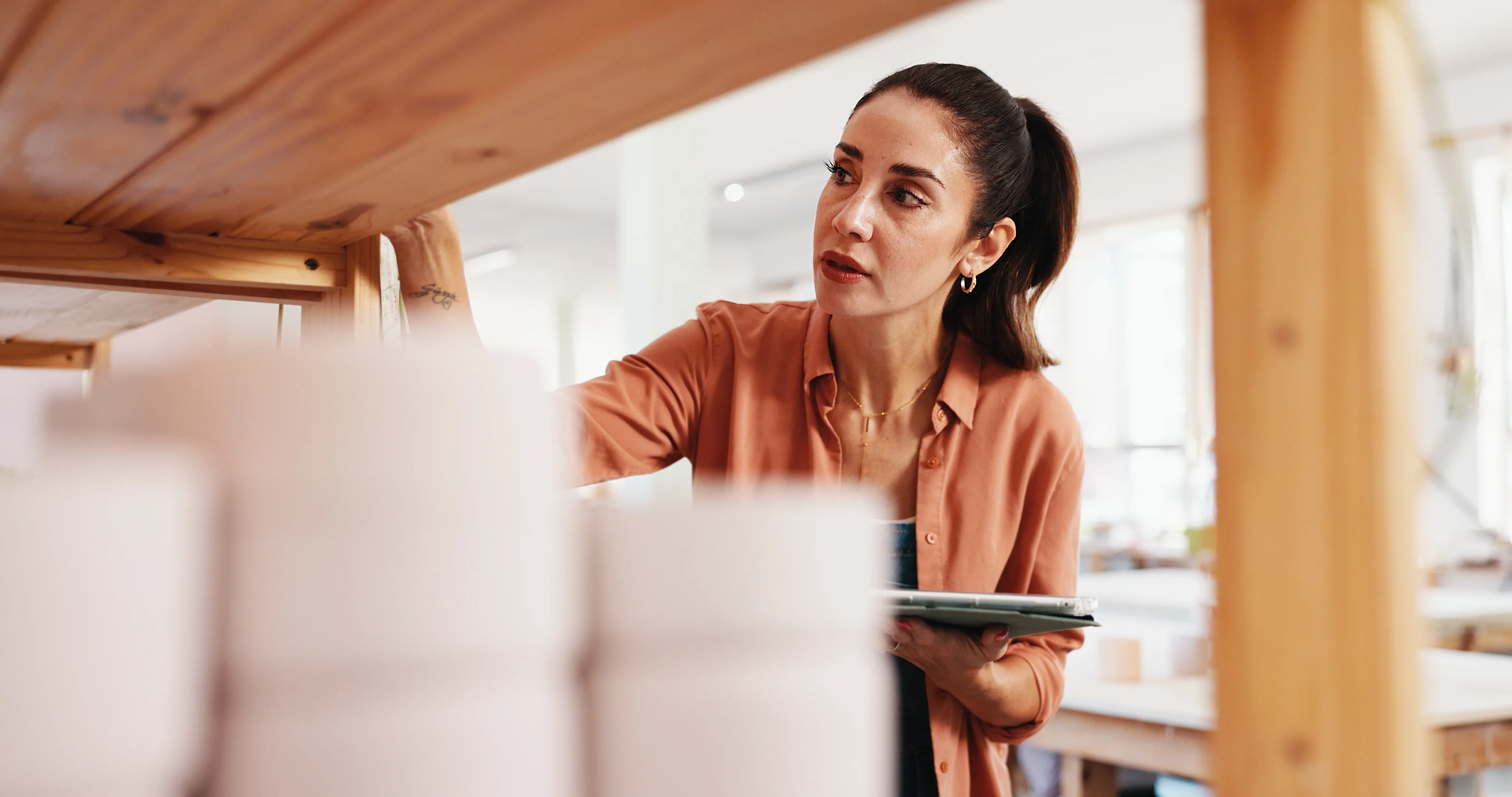 A woman looking at a shelf of what appears to be plates, counting the inventory.
