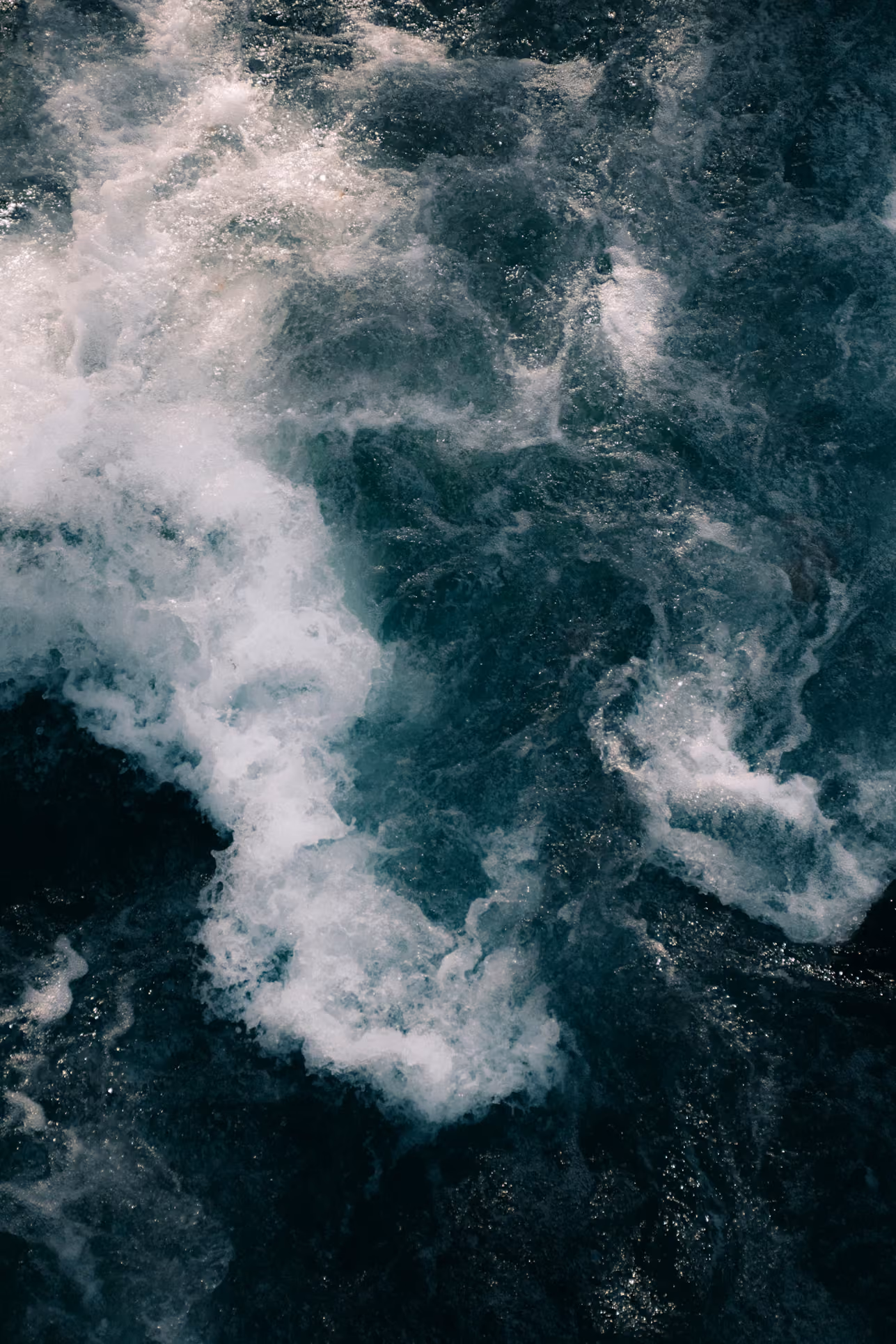 Foamy dark ocean water with white splashes and ripples.