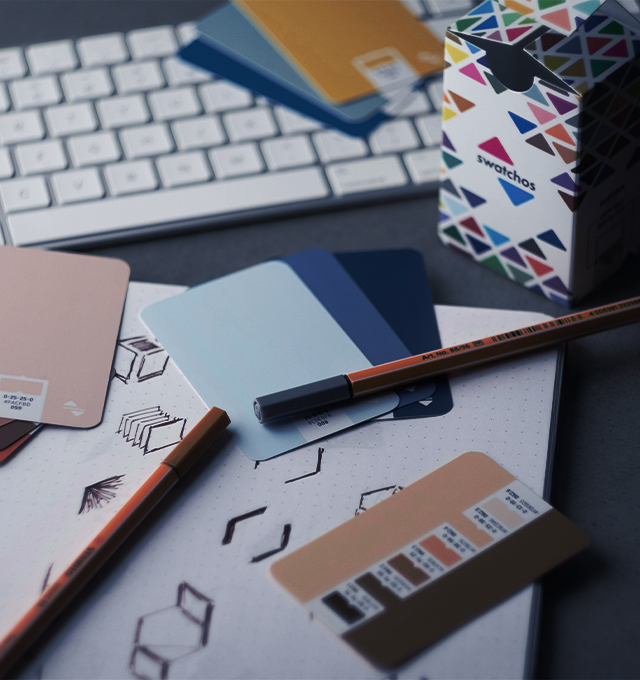 Branding materials including color swatches, sketches, and design tools arranged on a desk, representing brand identity development and creative strategy.