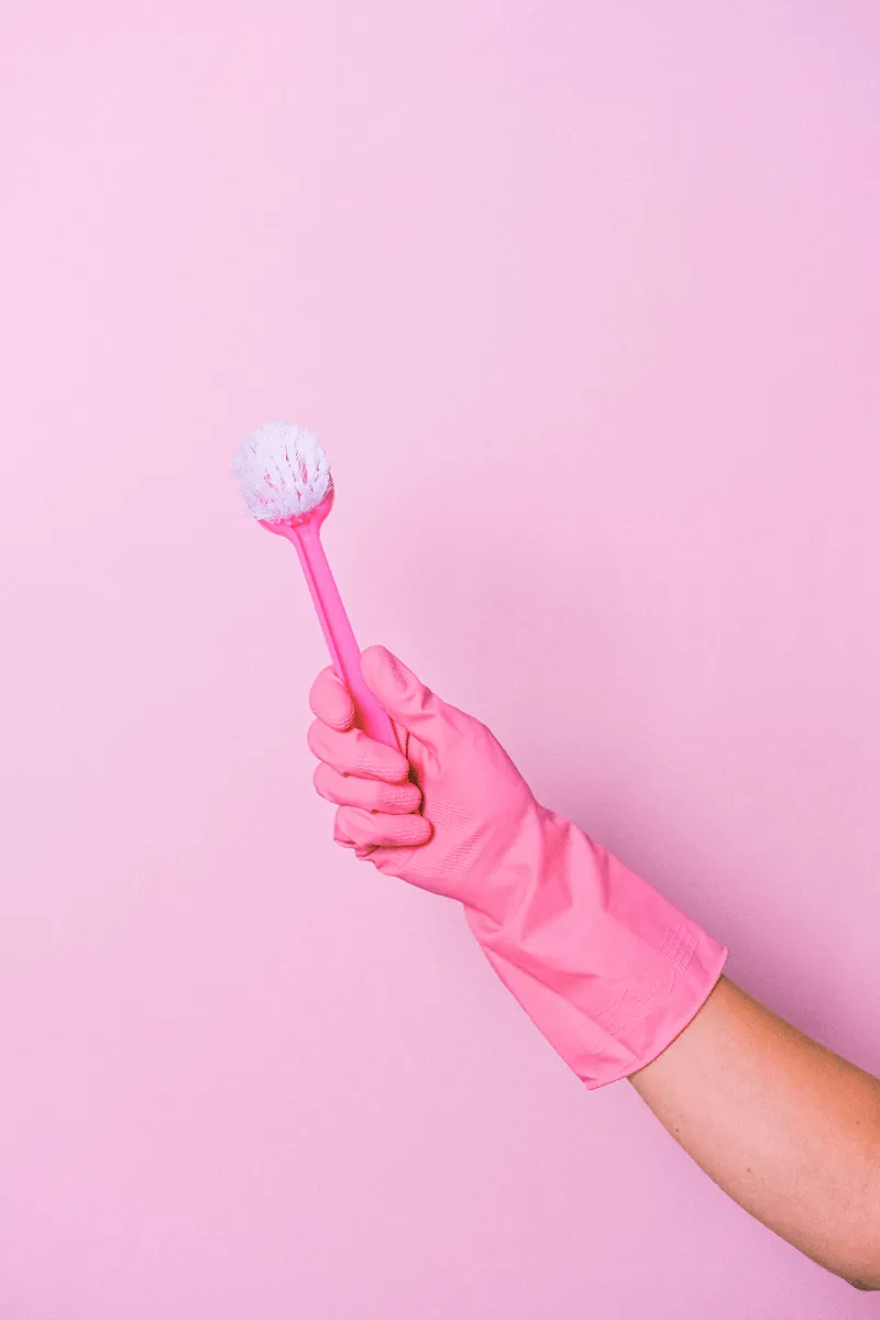 Main avec gant rose tenant une brosse de nettoyage professionnel Nickel Chrome