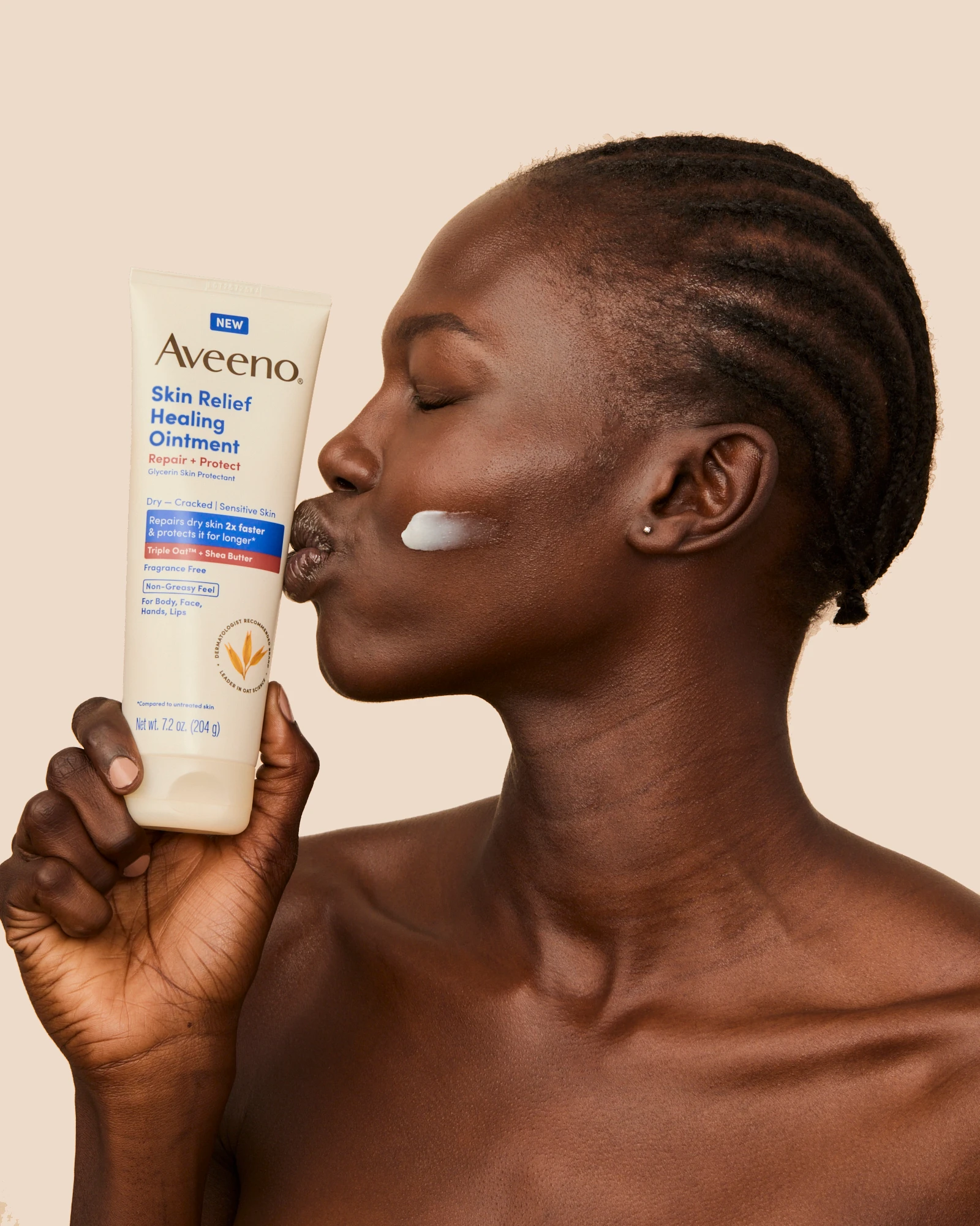A model holding an Aveeno tube beside her cheek.