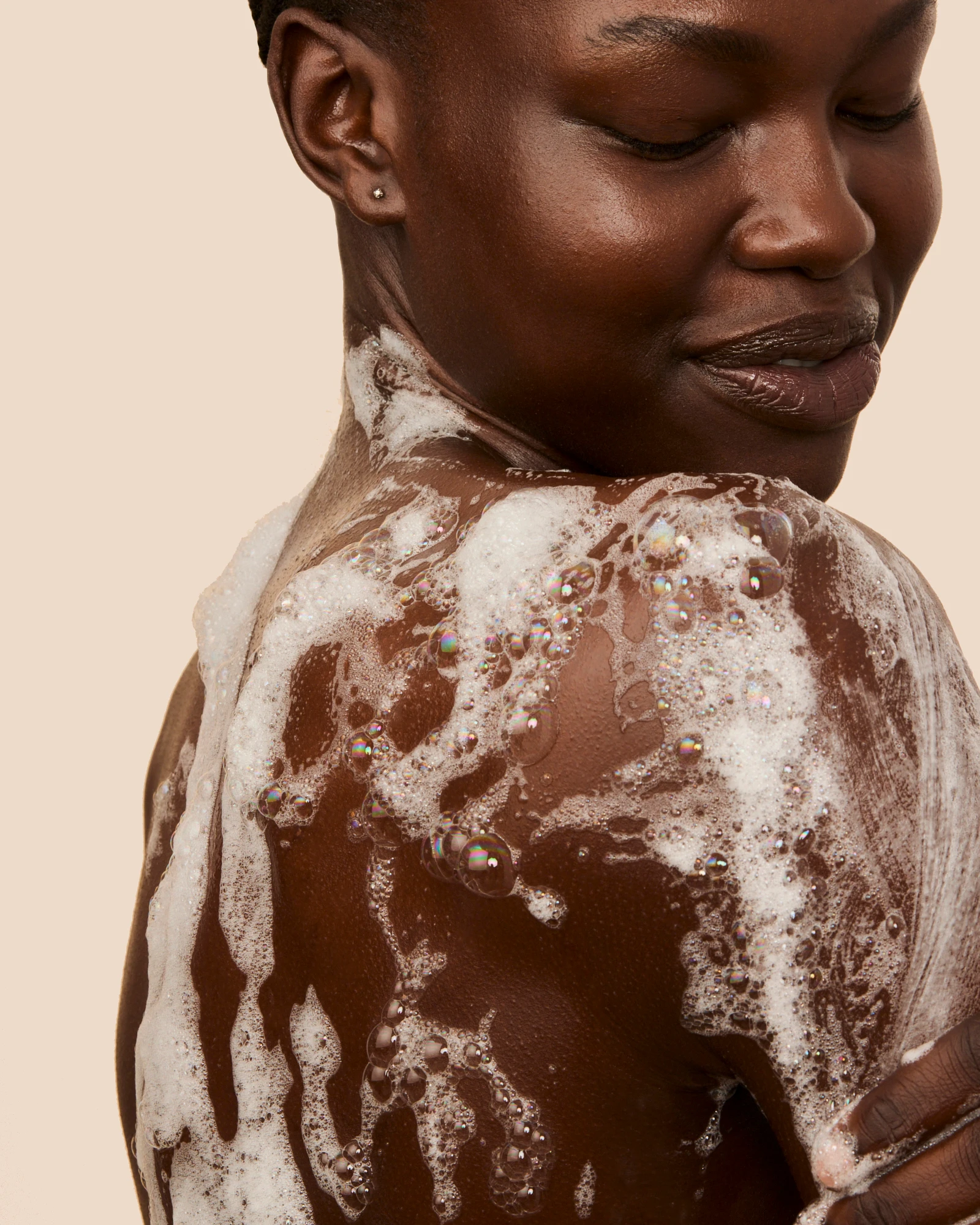 A model looking over her shoulder with lather on her back.