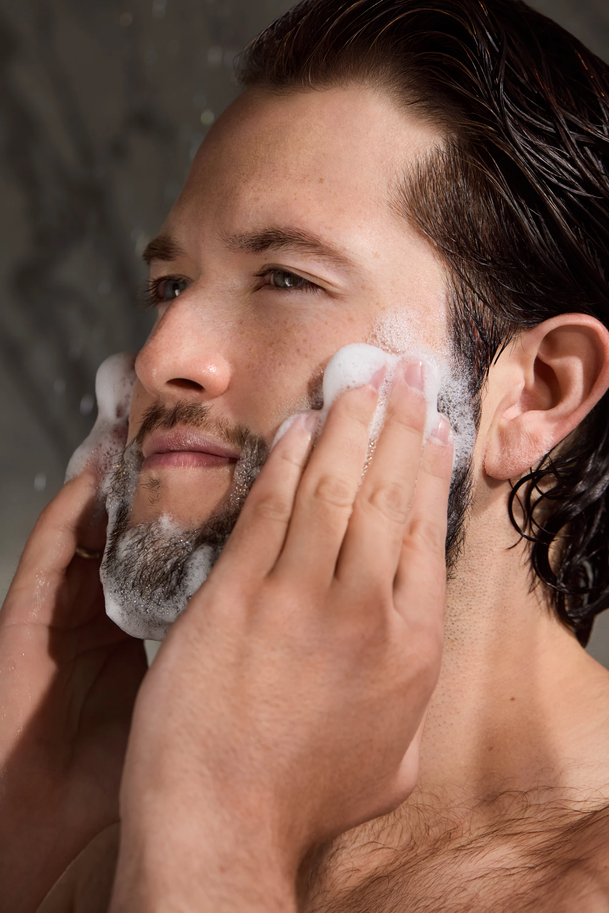 A model applying shaving foam to his cheeks.