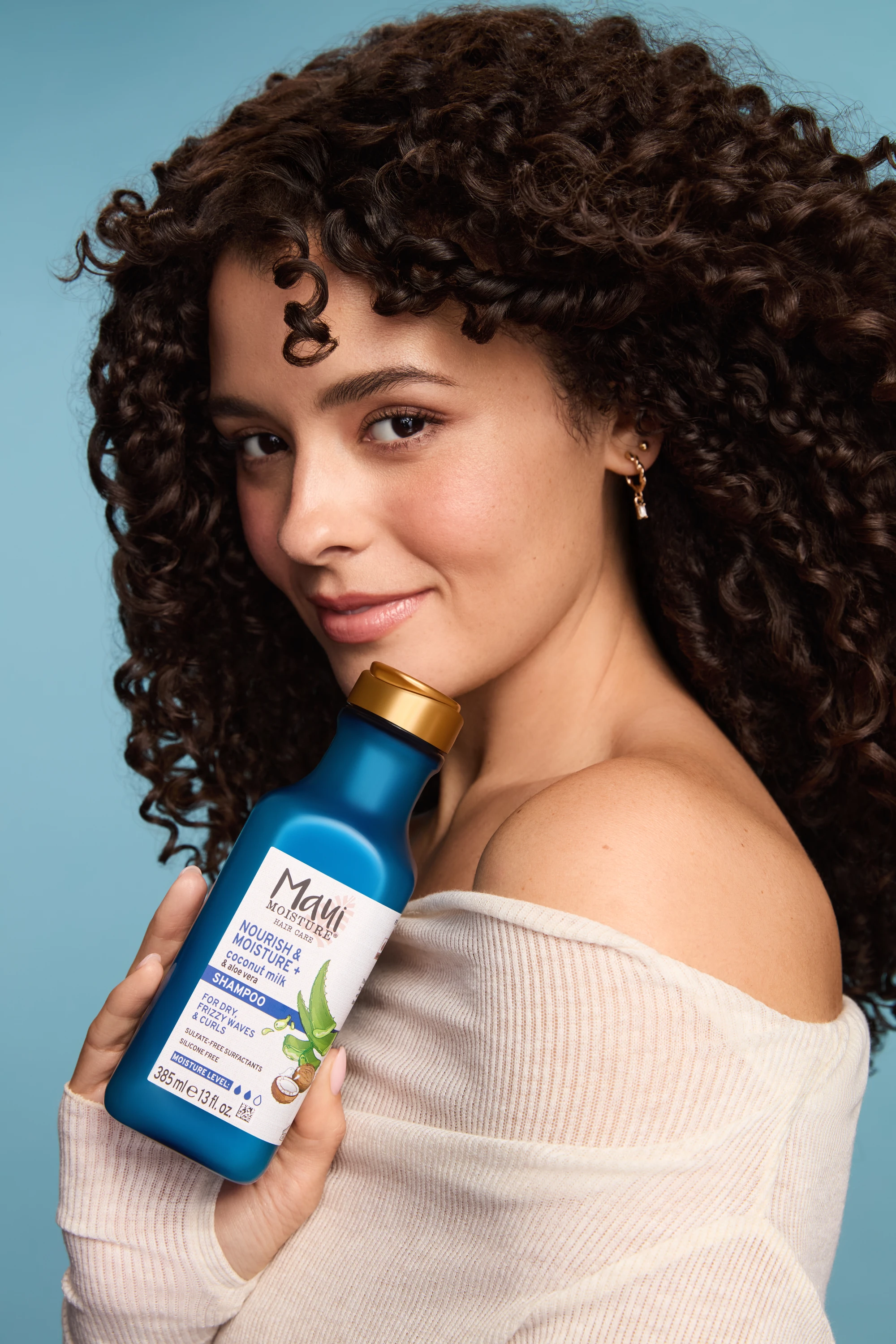 A model holding a blue Maui Moisture bottle beside her shoulder.