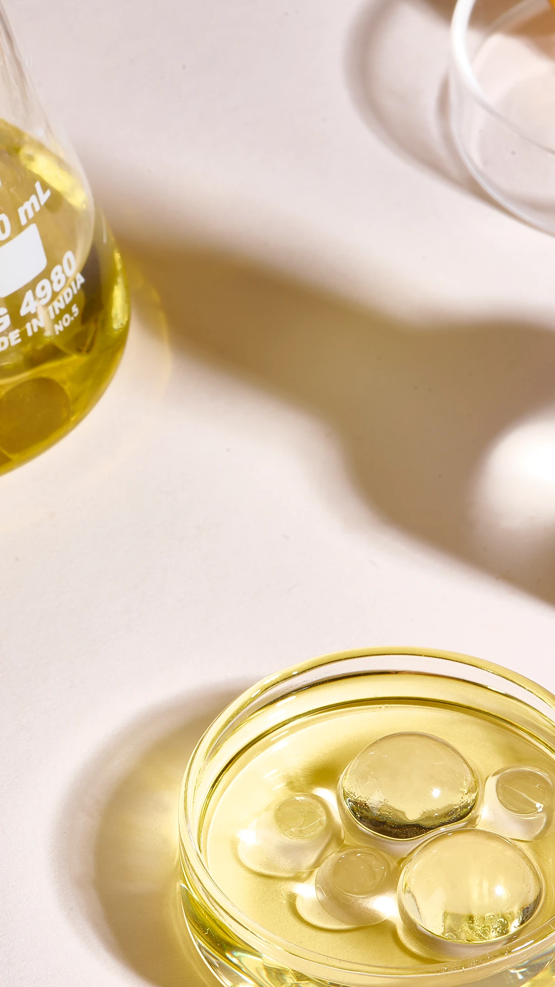 A dish of golden hair oil beside a bottle.