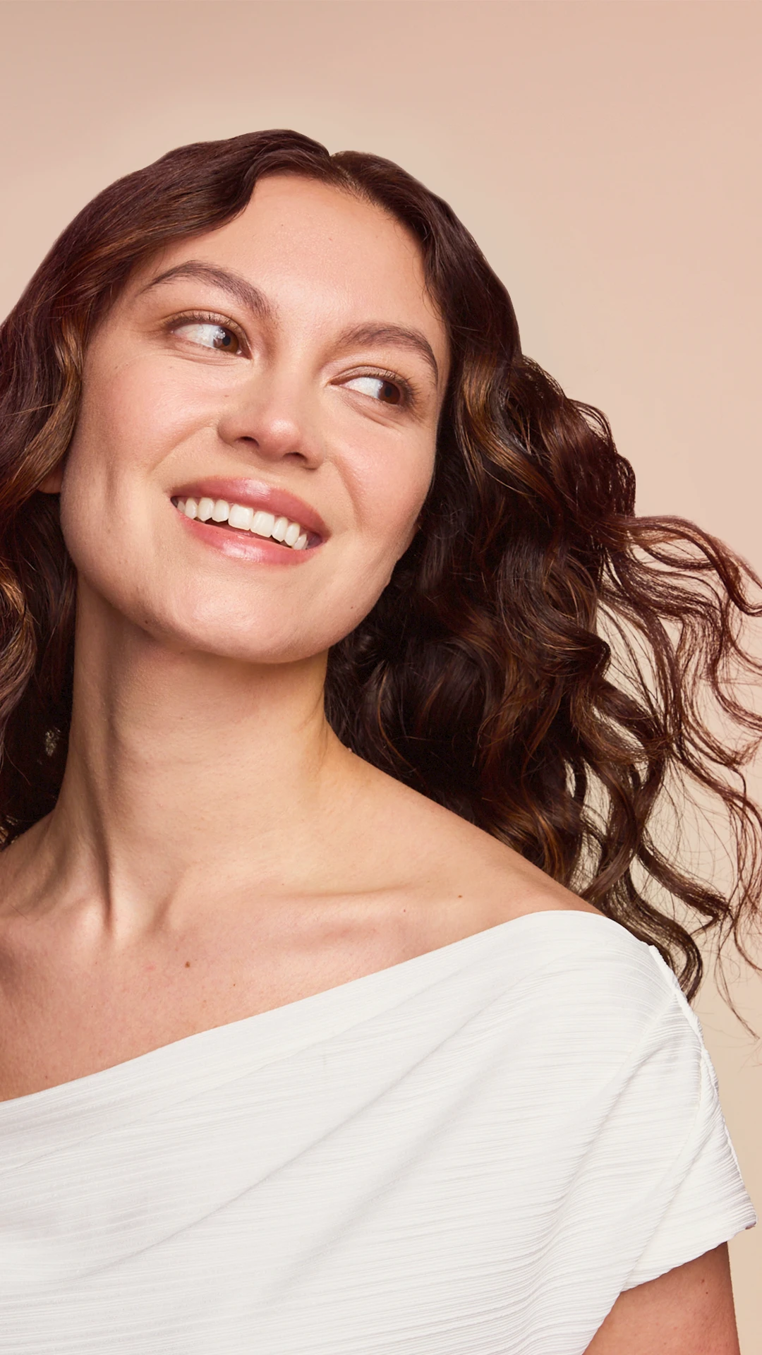 A smiling model with wavy brown hair.