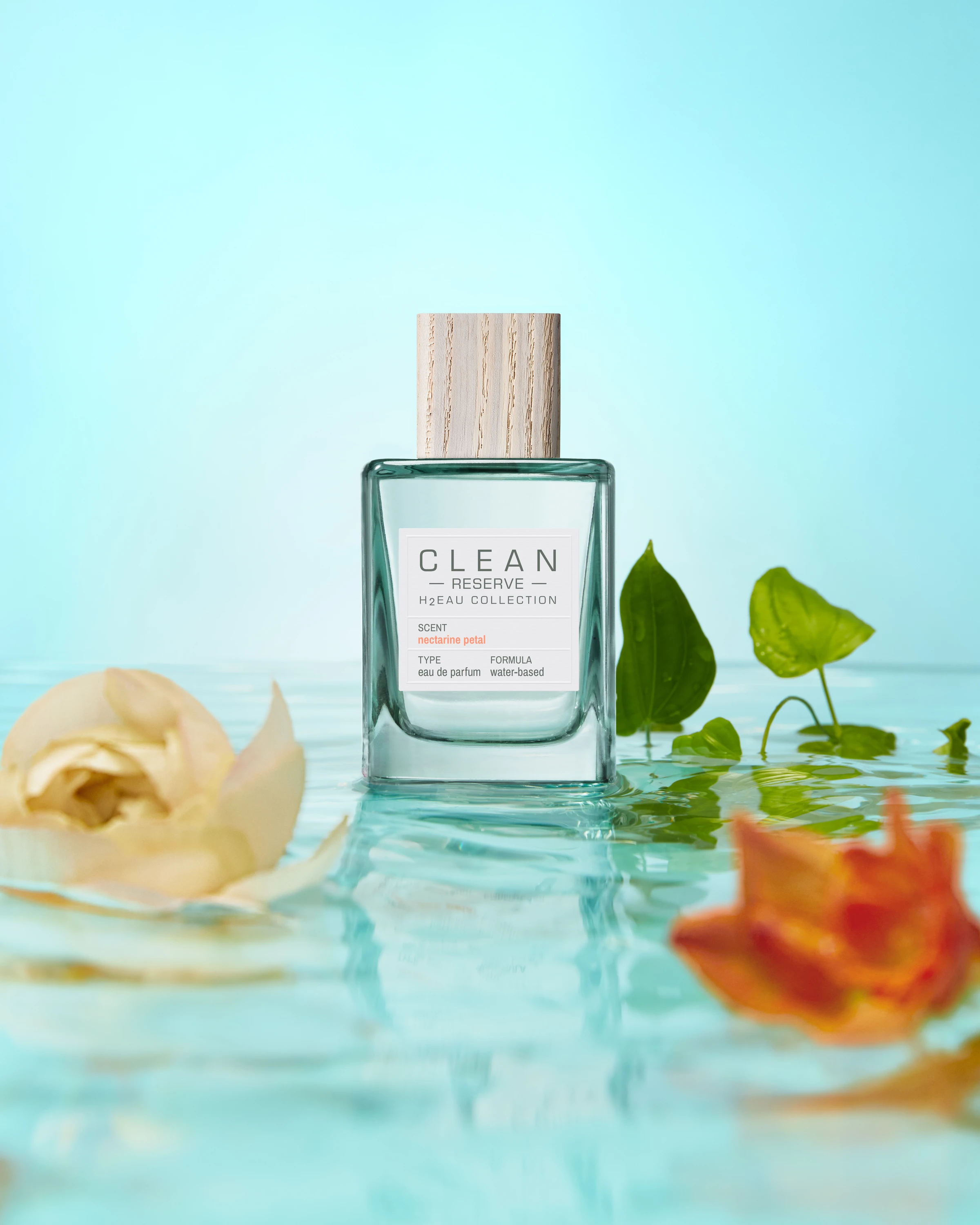 A Clean Reserve bottle surrounded by pale flowers and green leaves.