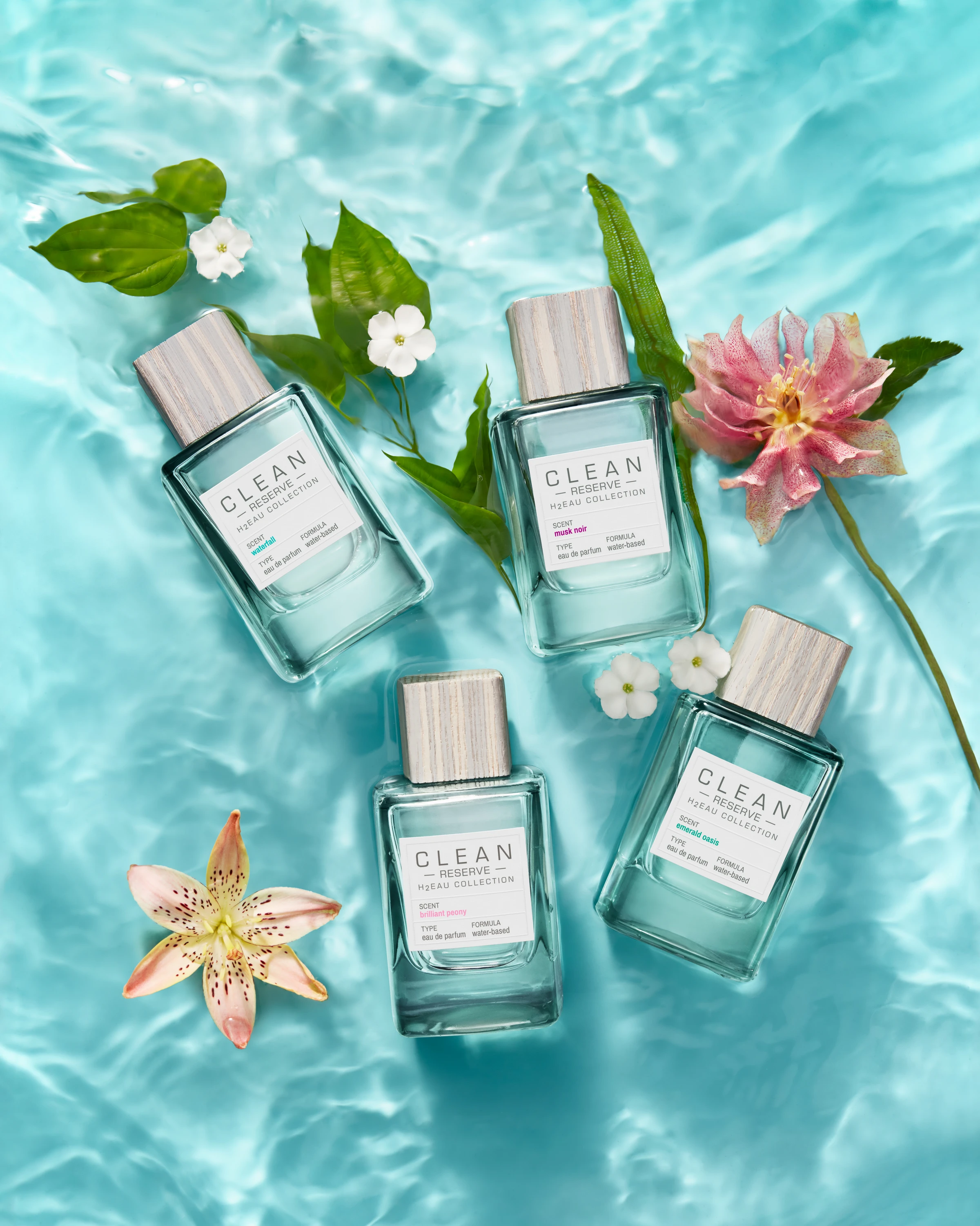 Four Clean Reserve H2eau bottles arranged in water with flowers.