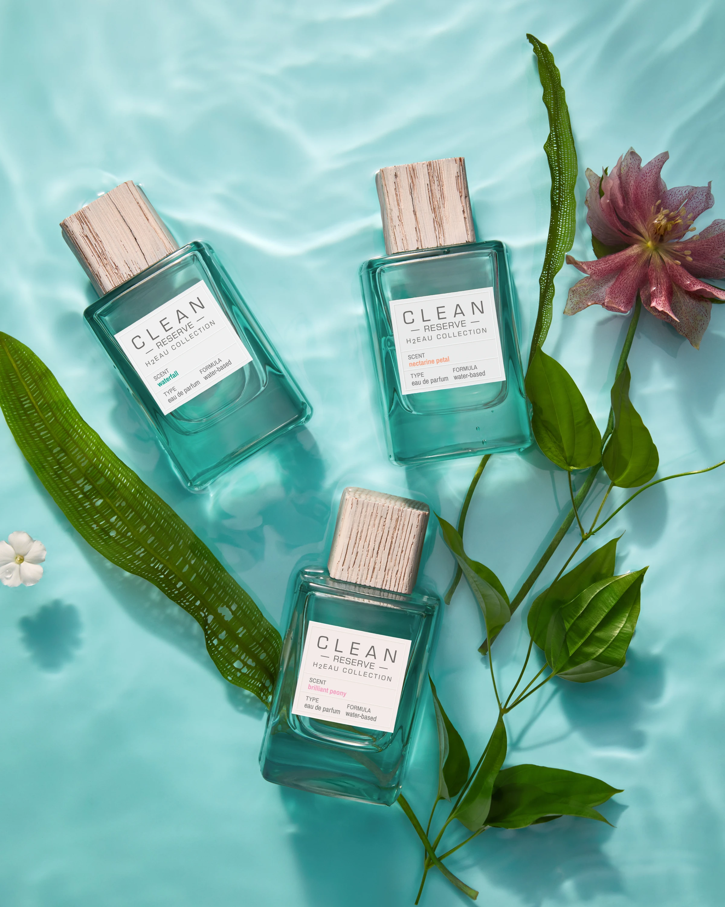 Three Clean Reserve bottles surrounded by leaves and flowers in water.